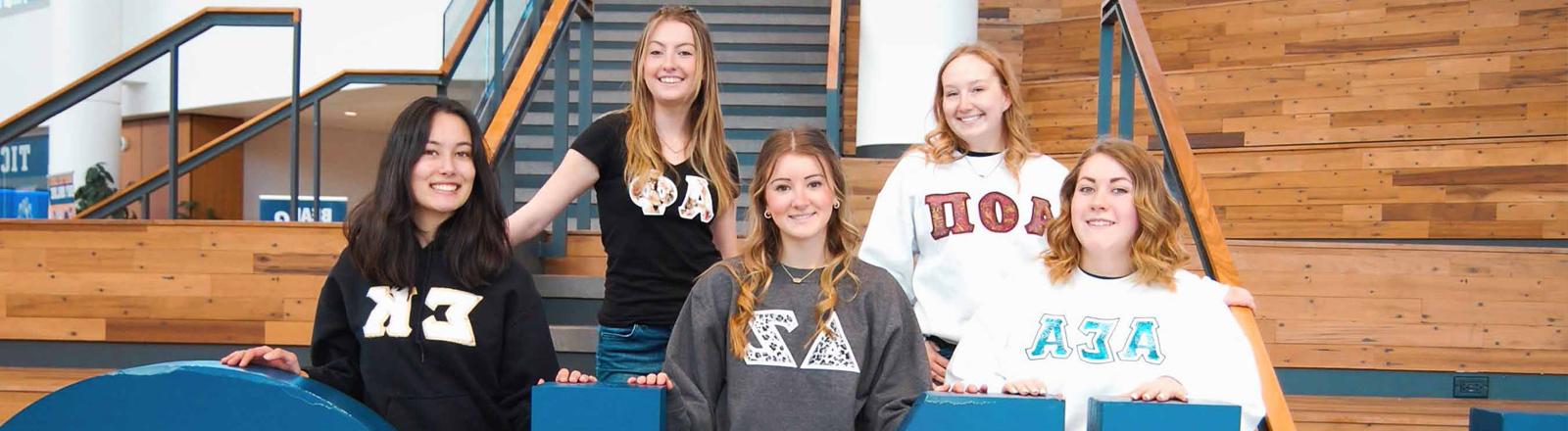 A group of NPC sorority women pose on a set of bleachers.